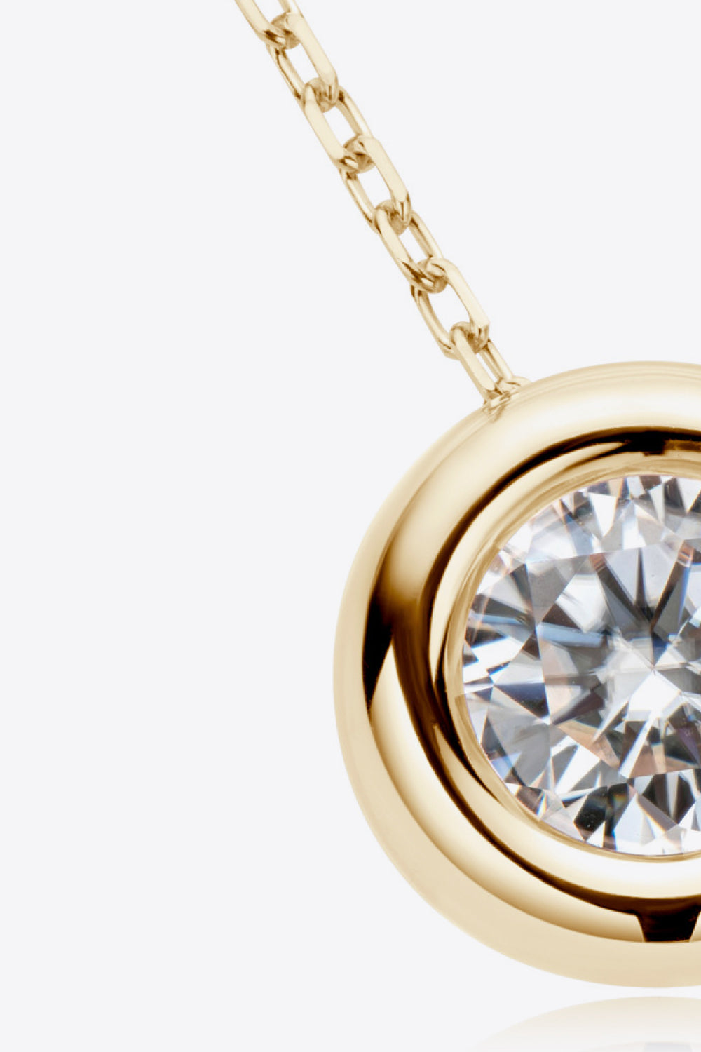 Gold necklace with bezel-set moissanite solitaire pendant and chain detail.