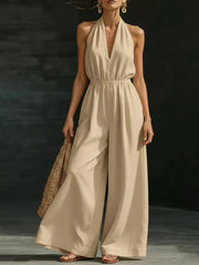 Apricot halter jumpsuit with wide legs and elastic waist, styled with sandals and a straw bag.