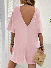 Blush pink ribbed knit romper with plunging back and short sleeves.