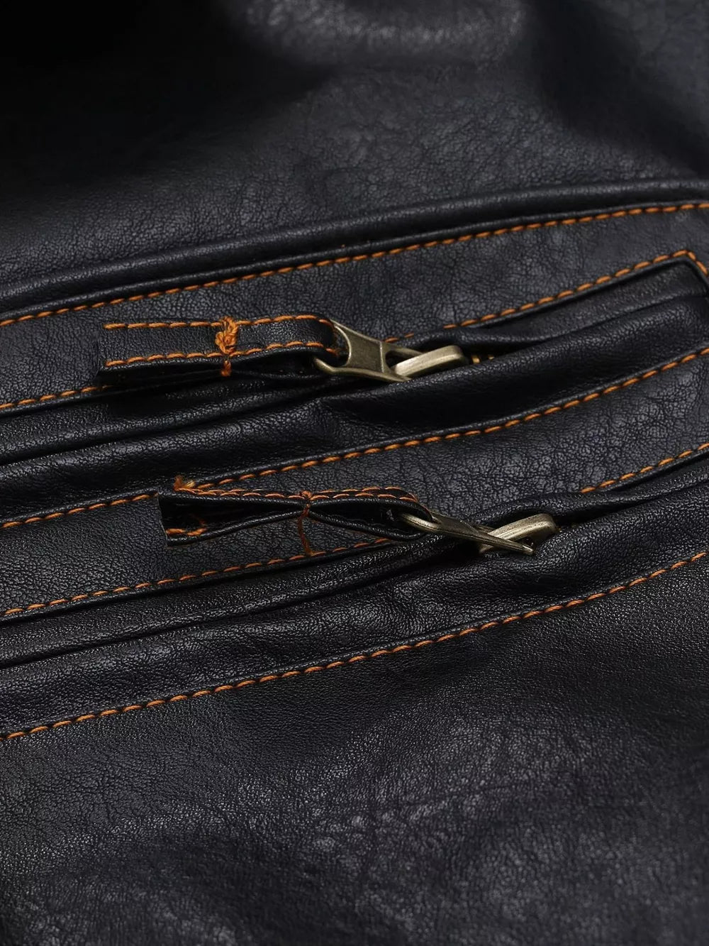 Black faux leather motorcycle coat detail with brass zippers and orange stitching.