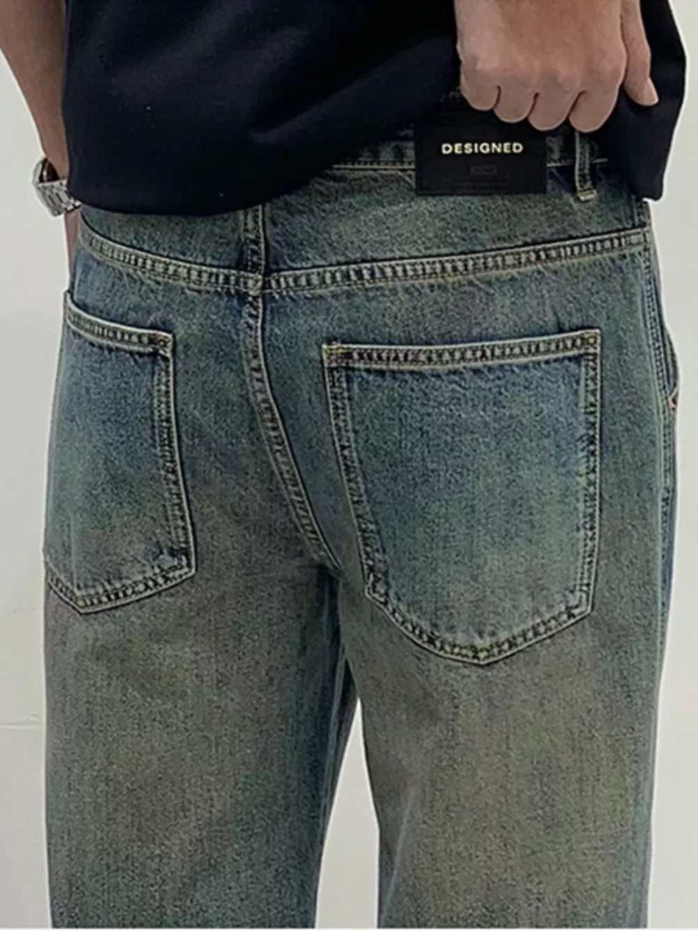Men's loose-fit blue-green washed cotton jeans with distressed details.