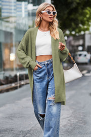 Sage open-knit longline cardigan with side slits and crew neck, styled with jeans.