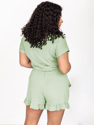 Off-shoulder romper in Gum Leaf green with ruffled hem shorts and short sleeves.
