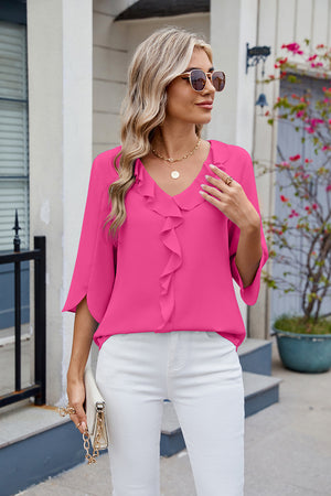 Hot pink V-neck blouse with ruffle detail and flutter sleeves.
