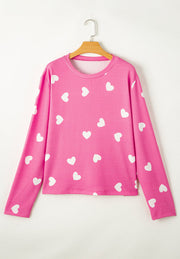 Hot pink long sleeve top with white hearts pattern, round neck.