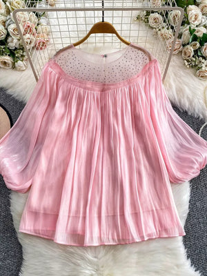 Pink sheer blouse with rhinestone-embellished neckline and balloon sleeves.
