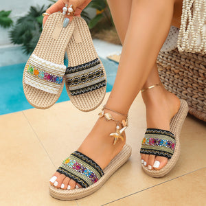 Bohemian woven strap flat sandals with colorful embroidered detail and natural rope sole.