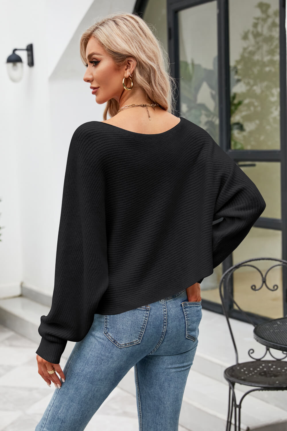 Black ribbed knit sweater with off-shoulder boat neck and balloon sleeves.