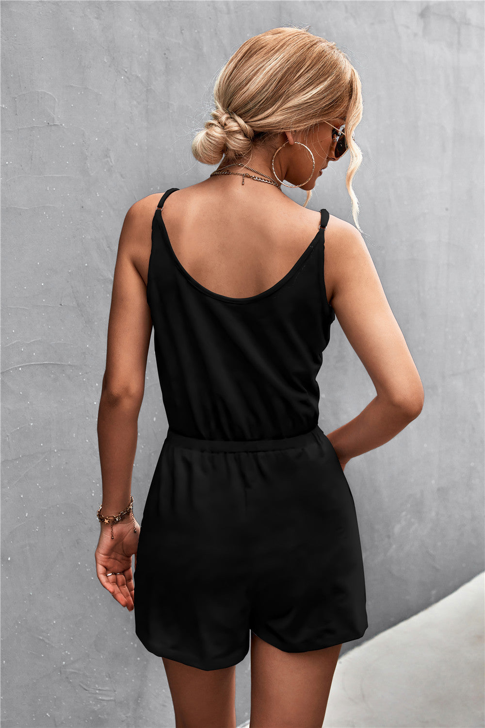 Black V-neck drawstring romper with adjustable spaghetti straps and elastic waist.