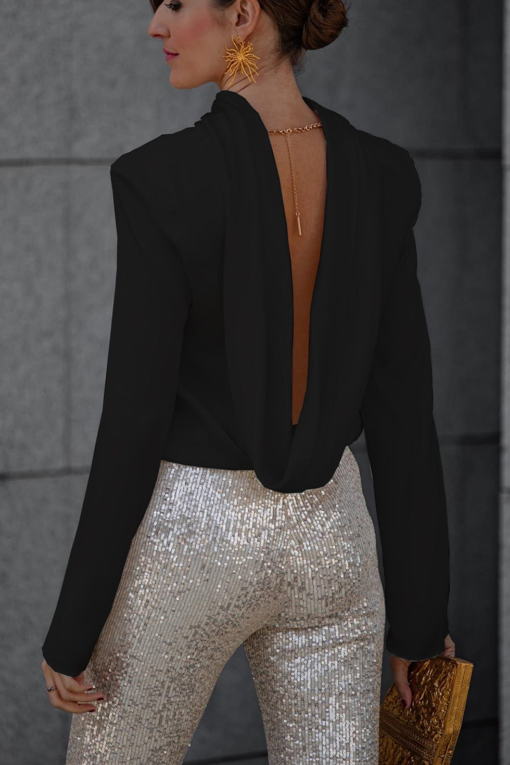 Black silk blouse with a draped back and gold chain detail, paired with sequined pants.