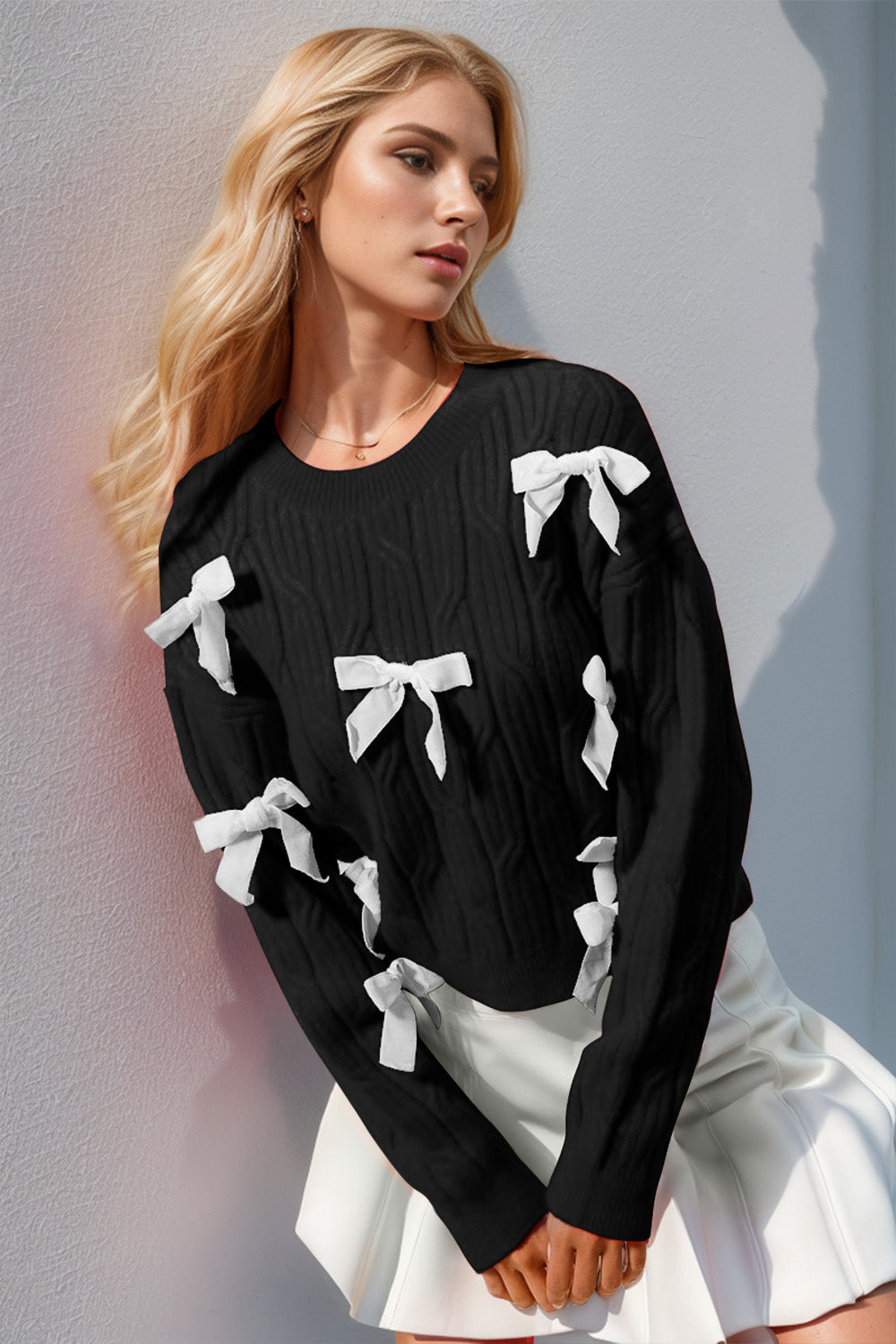 Black cable knit sweater with white bow embellishments and crew neck.