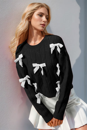 Black cable knit sweater with white bow embellishments and crew neck.