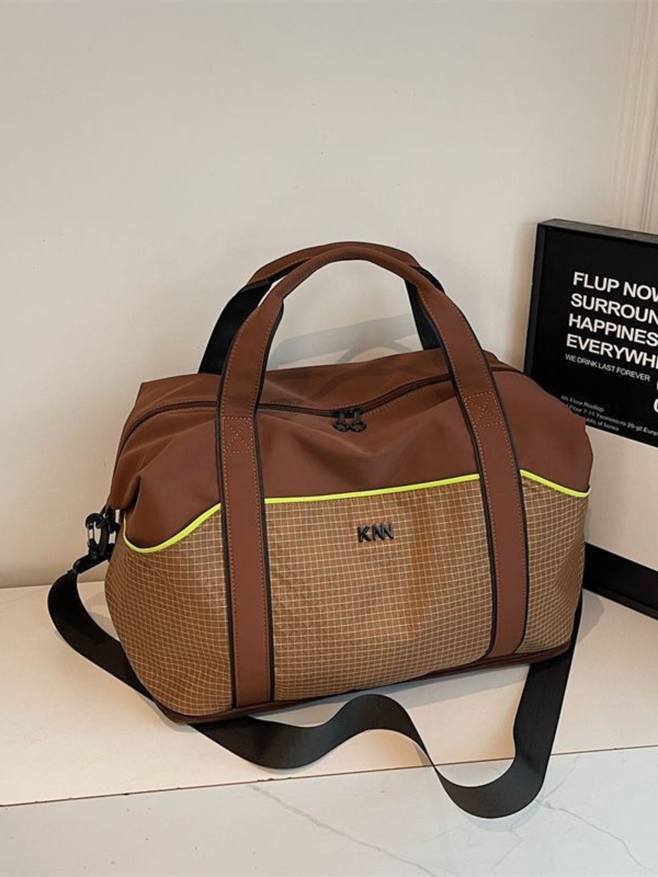 Brown nylon duffel bag with grid pattern, neon trim, and detachable strap.