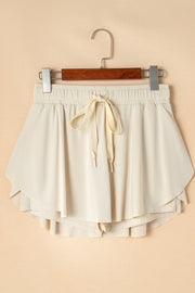 Beige ruffled skort with tie waist detail and elastic waistband.