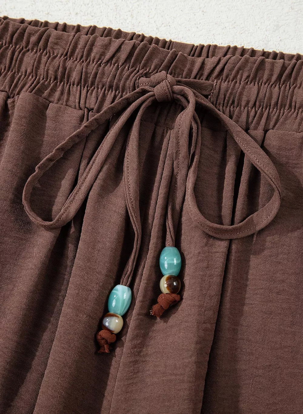 Brown relaxed wide-leg maternity pants with drawstring and beaded detail.