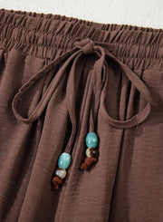 Brown relaxed wide-leg maternity pants with drawstring and beaded detail.