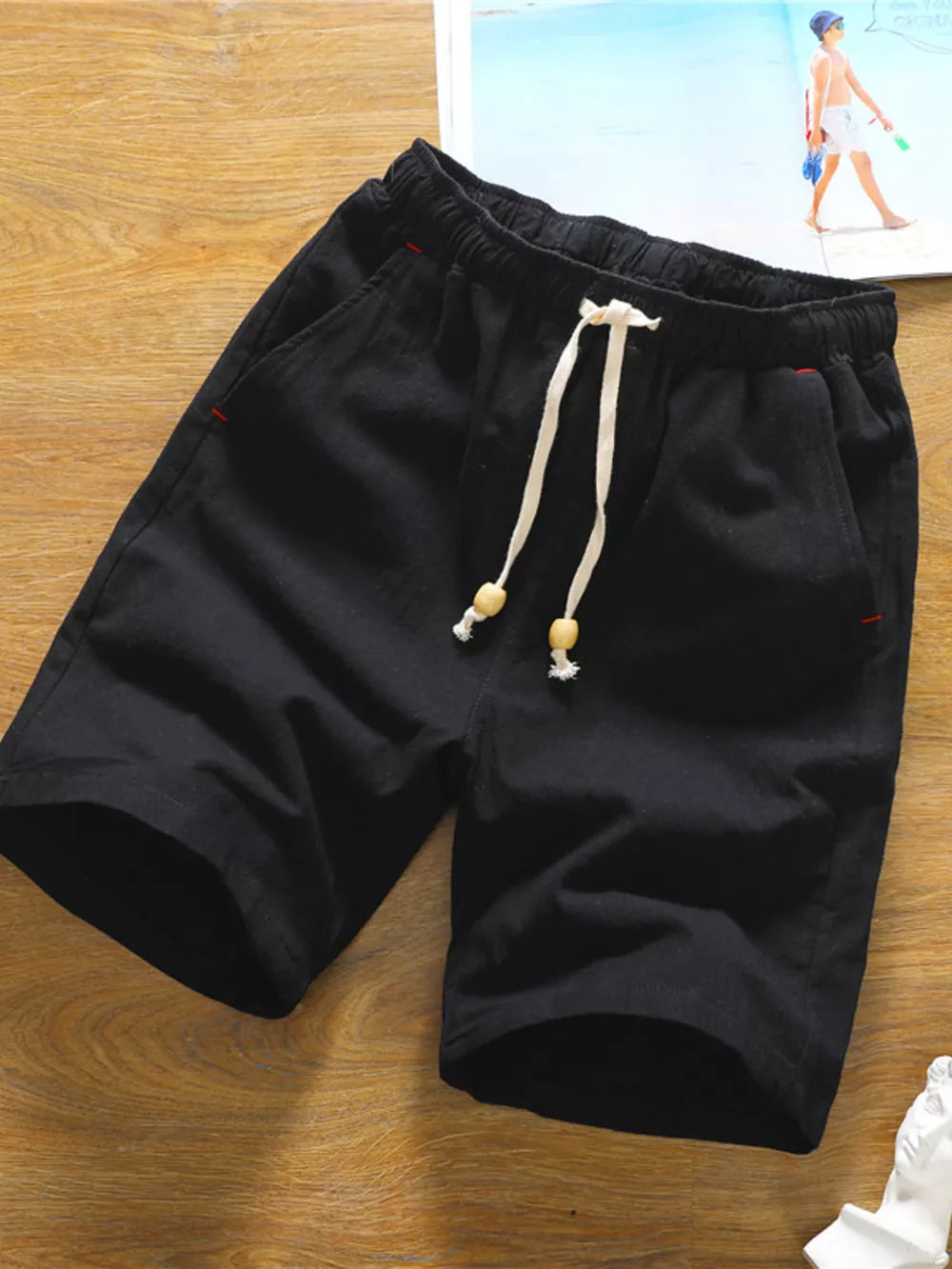 Black chino shorts with drawstring and red accent stitching.