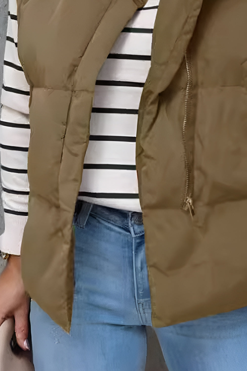 Padded stand collar vest in olive brown with a zip closure, layered over a striped long-sleeve shirt and jeans.