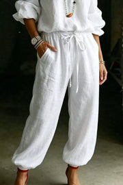 White cotton drawstring pants with pockets, part of a two-piece set.