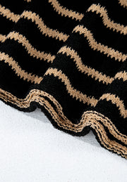 Black knit jumper with horizontal beige zigzag stripes and a textured hem.