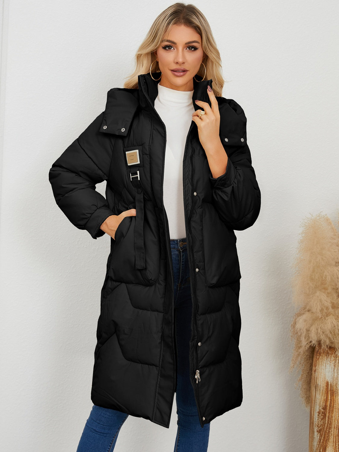 Black quilted puffer parka with buckle detail and belt, long sleeves, hood.