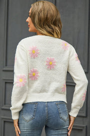 White textured knit sweater with pink daisy motif and yellow centers.