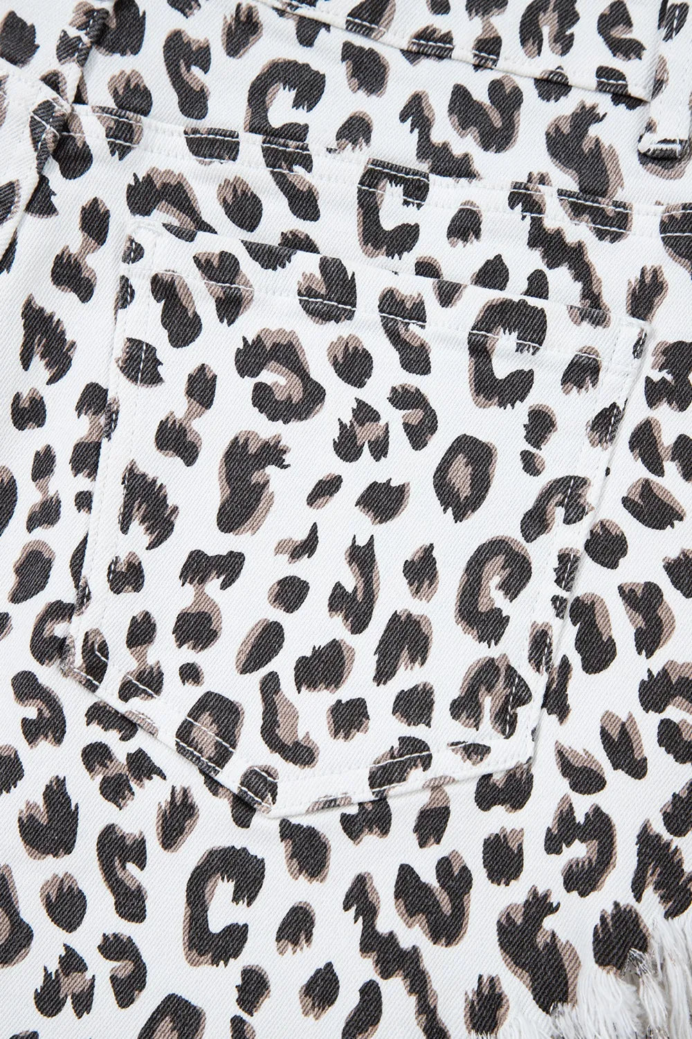 Leopard print denim shorts with frayed hem detail.