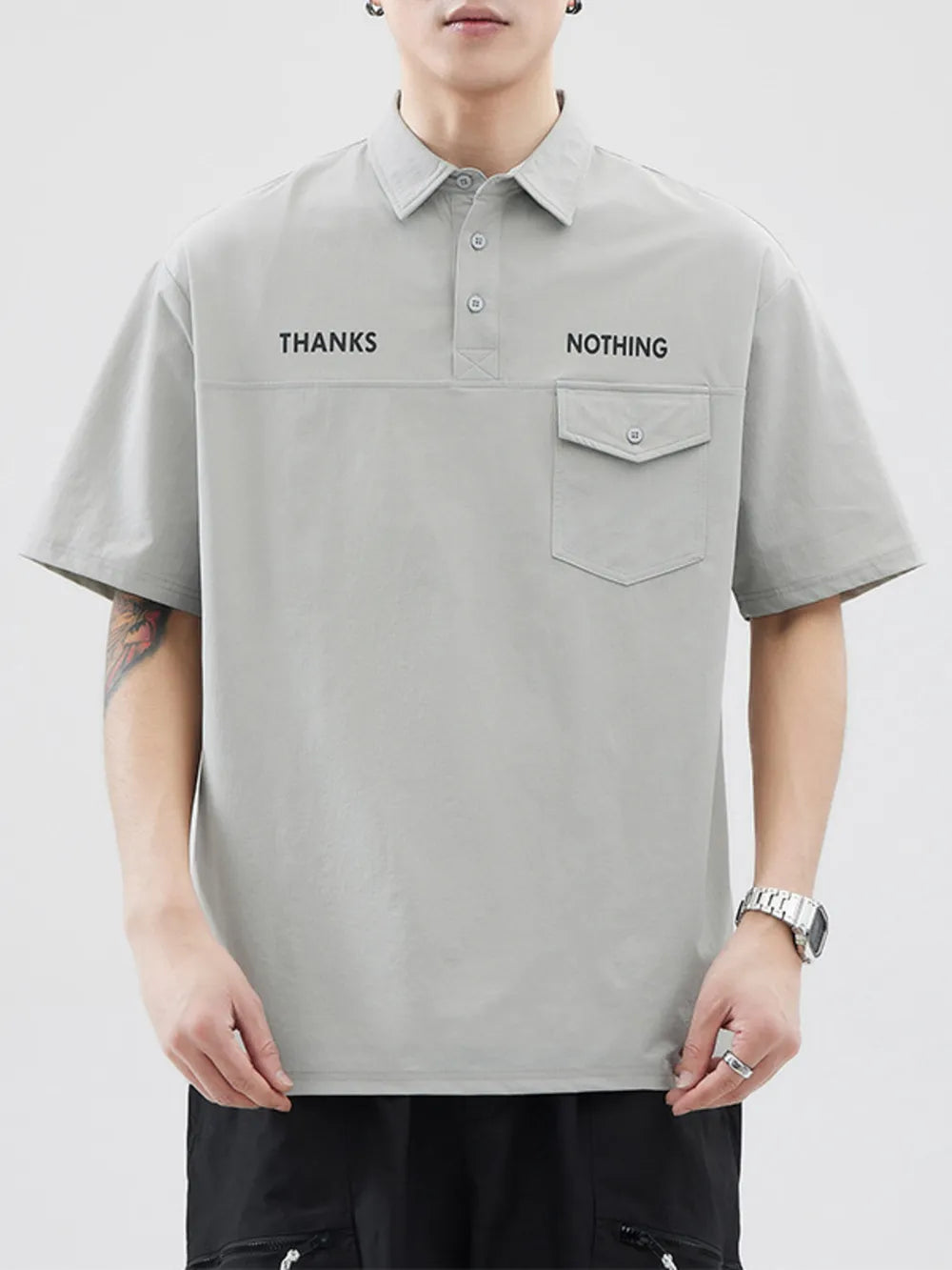 Light gray polo shirt with button detail, chest pocket, and text graphic.