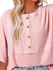 Pink waffle-knit t-shirt with button detail and textured hem.