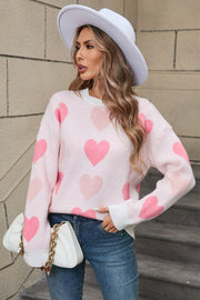 Pink knit crewneck pullover sweater with allover heart motif and white trim.