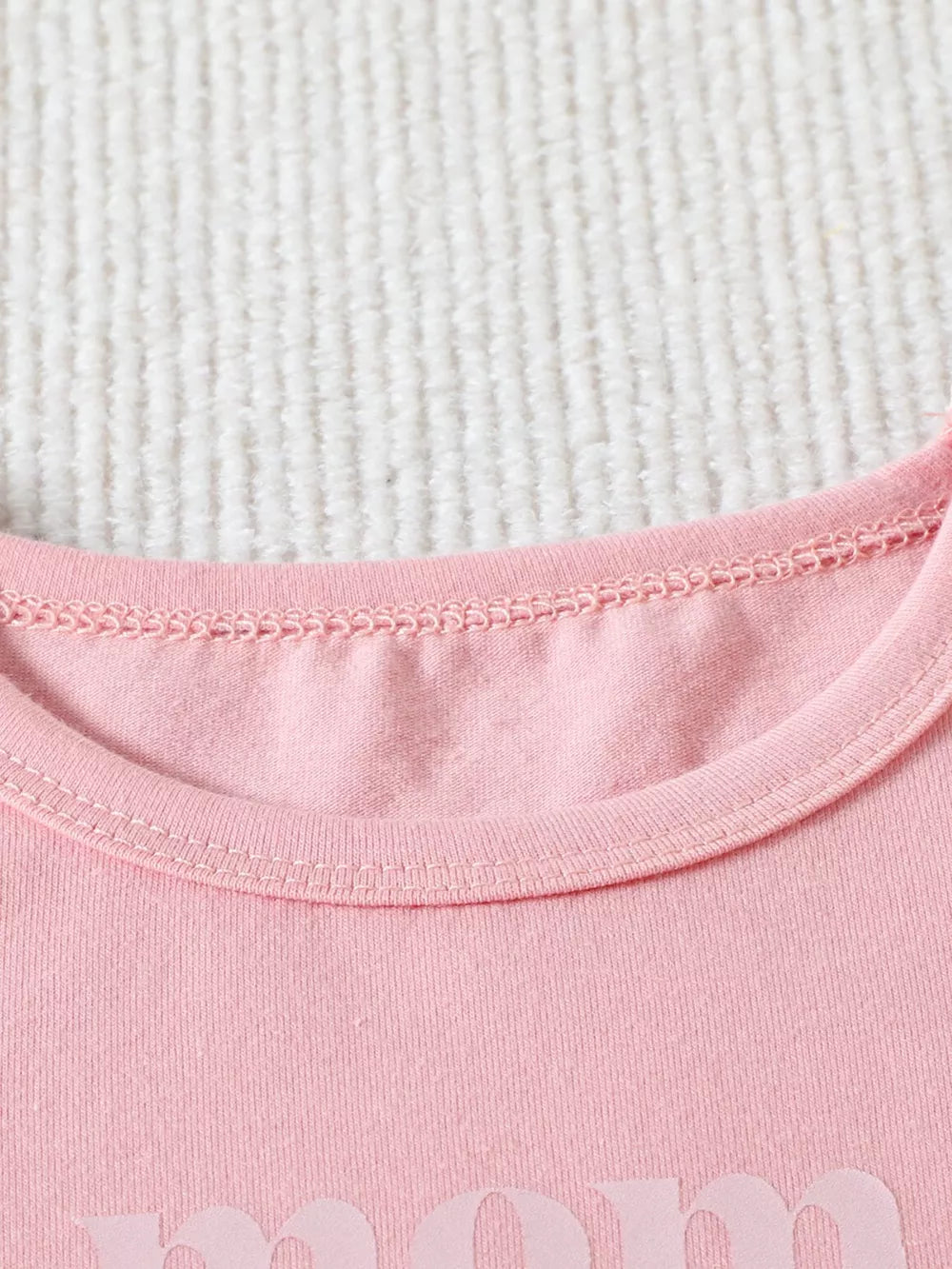 Blush pink cotton baby tee with "Mama" graphic detail, crew neck.
