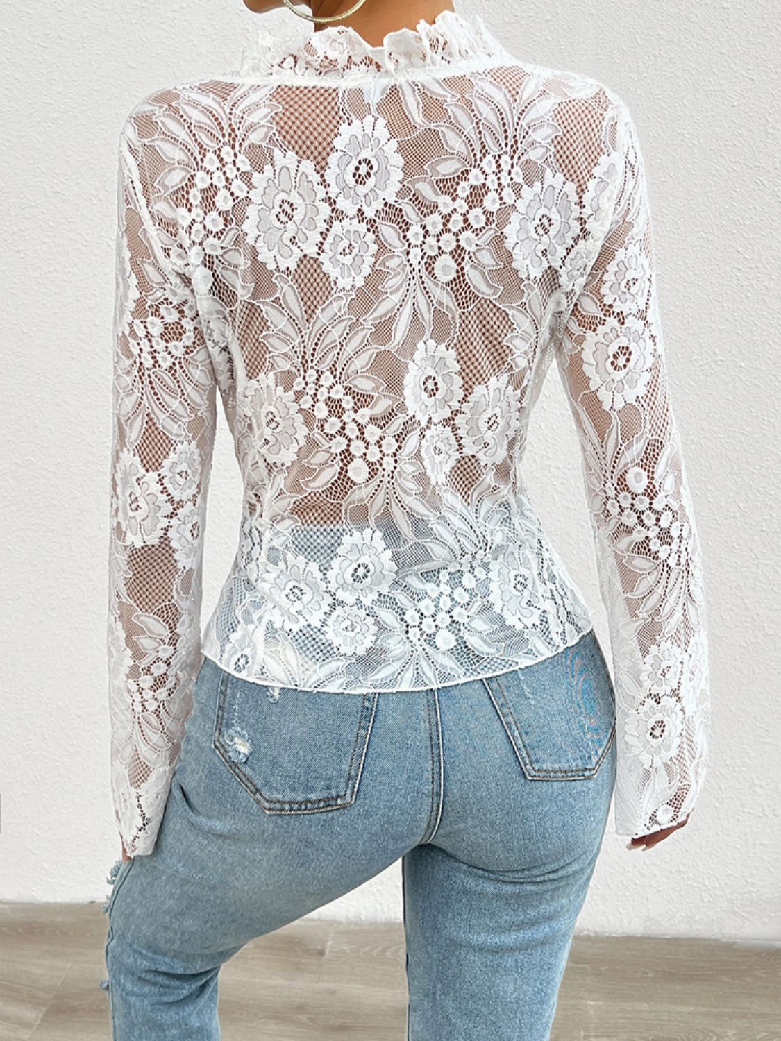 White lace blouse with floral pattern and ruffled neckline, long sleeves.