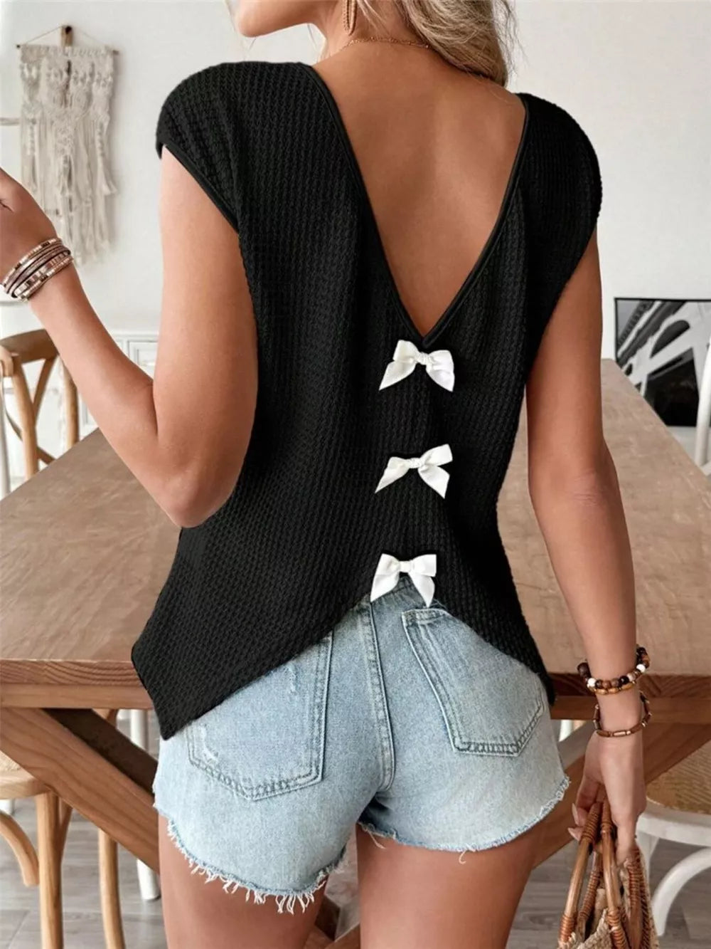 Black waffle knit shirt with V-neck and cap sleeves, featuring three white bow details down the back.