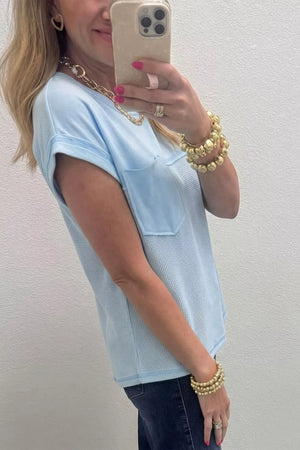 Light blue waffle knit t-shirt with short sleeves, a chest pocket, and a curved hem.