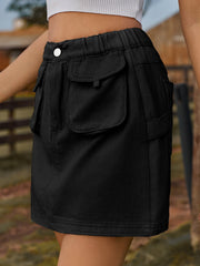 Black denim mini skirt with elastic waist and button closure, featuring utility pockets.