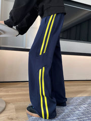 Navy blue sweatpants with yellow stripes and wide legs.