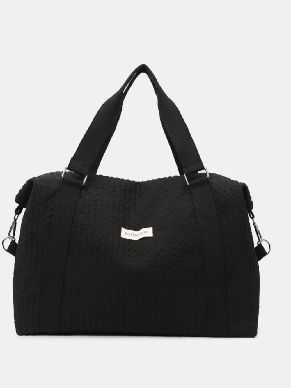 Black waffle-weave weekend bag with silver hardware and adjustable strap.
