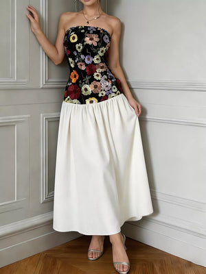 Floral embroidered strapless maxi dress with a black bodice and white skirt.