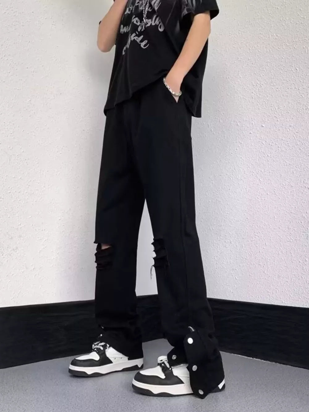 Black distressed loose-fit jeans with snap detail and adjustable hem