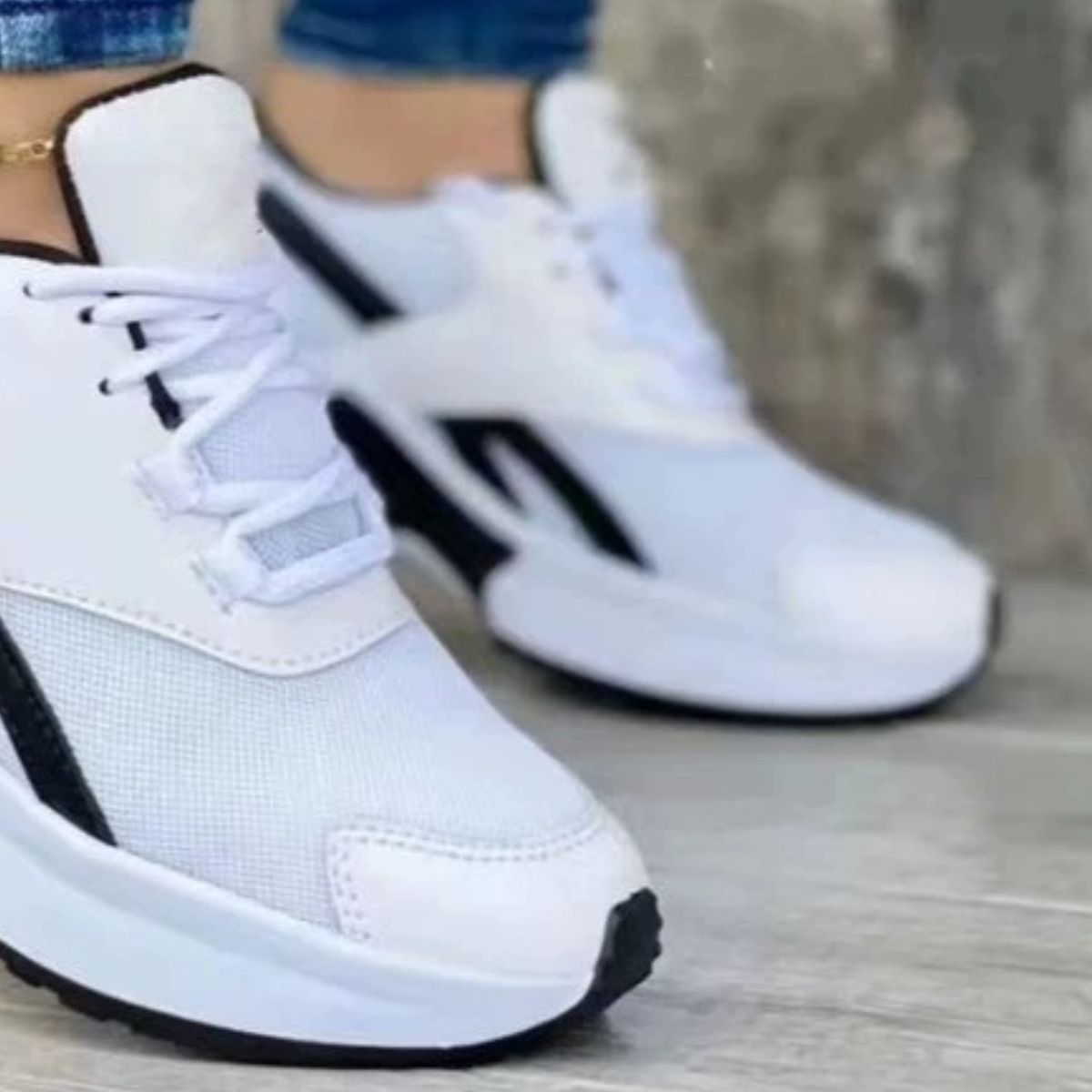 White lace up air cushion sneakers with black accents and a chunky sole.
