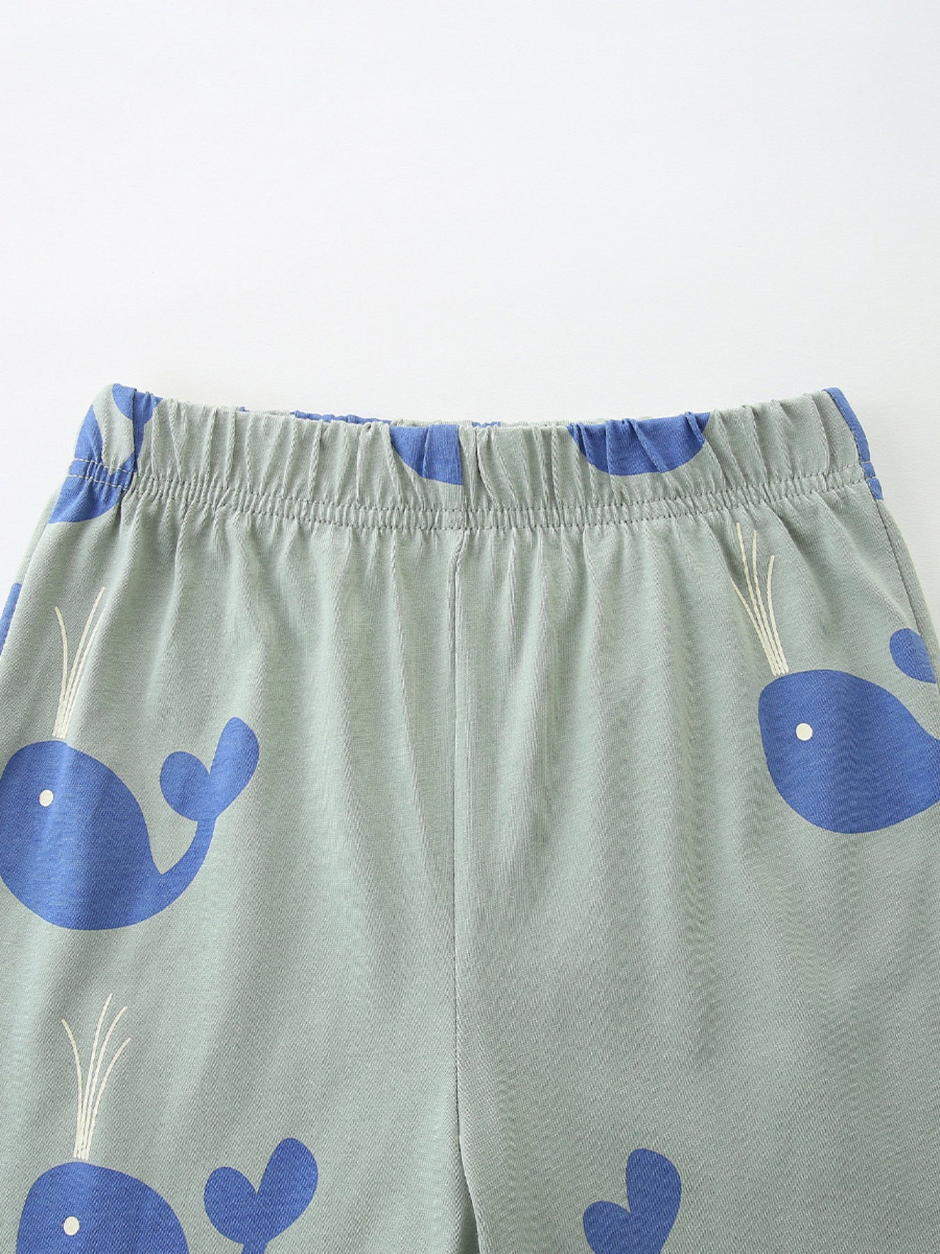 Toddler boys' light green cotton shorts with blue whale print and elastic waistband.