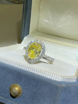 Yellow pear-cut moissanite ring with diamond halo in a jewelry box.