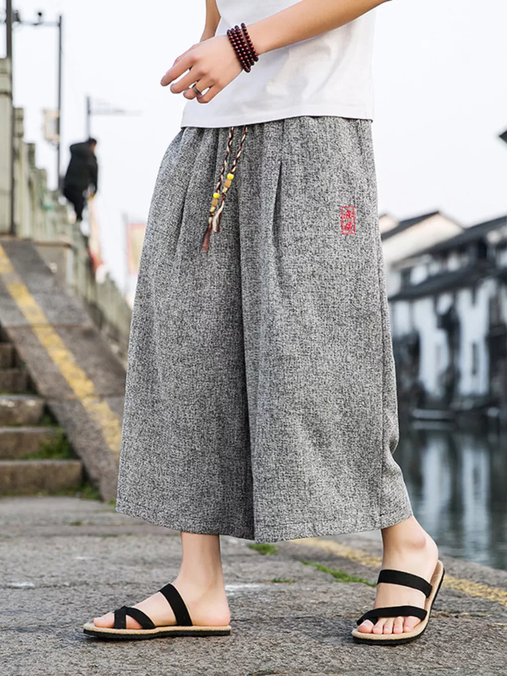Gray relaxed fit wide-leg casual pants with drawstring and red embroidered detail.