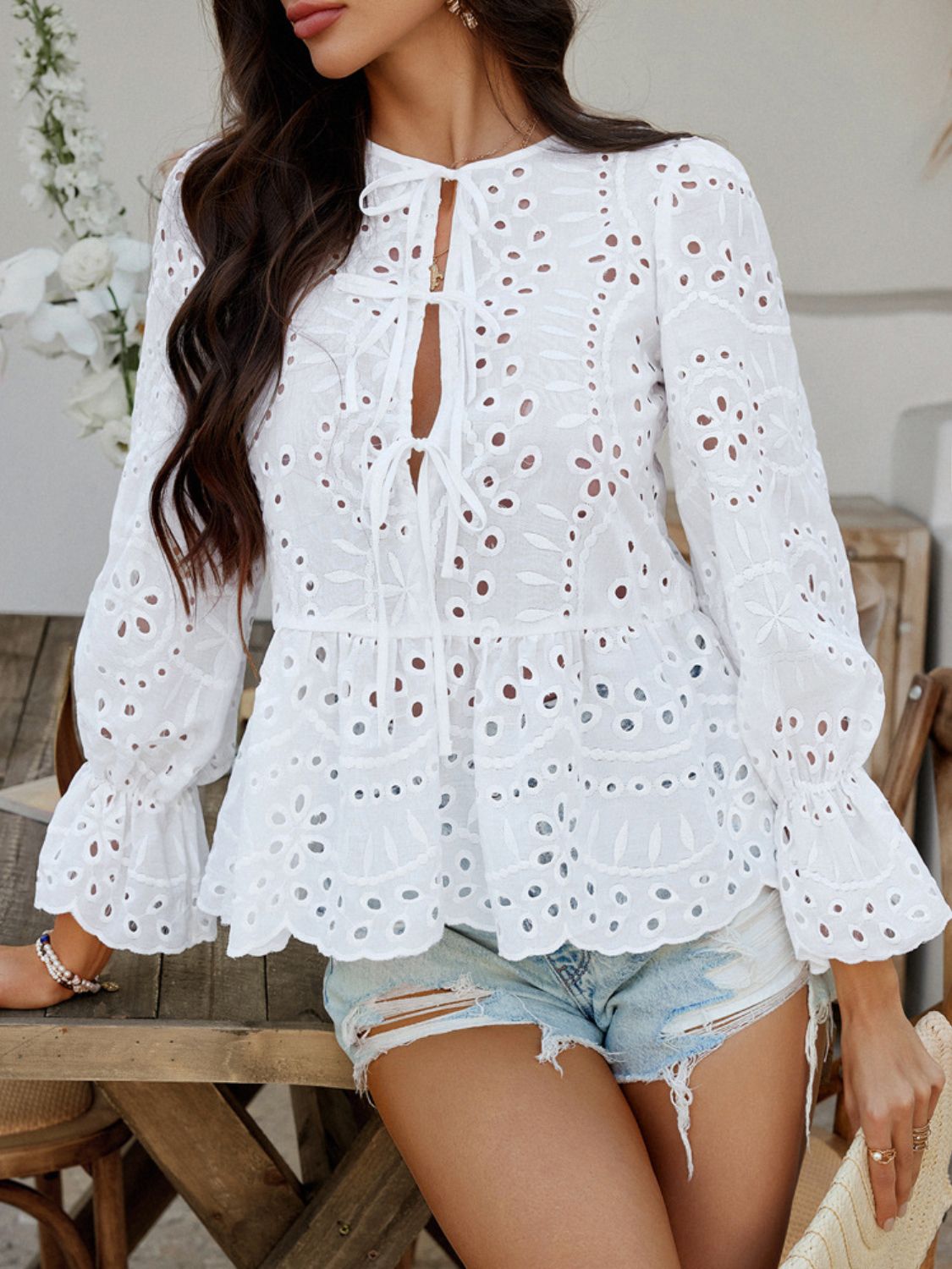 White eyelet embroidered peplum blouse with tie neck and flared sleeves