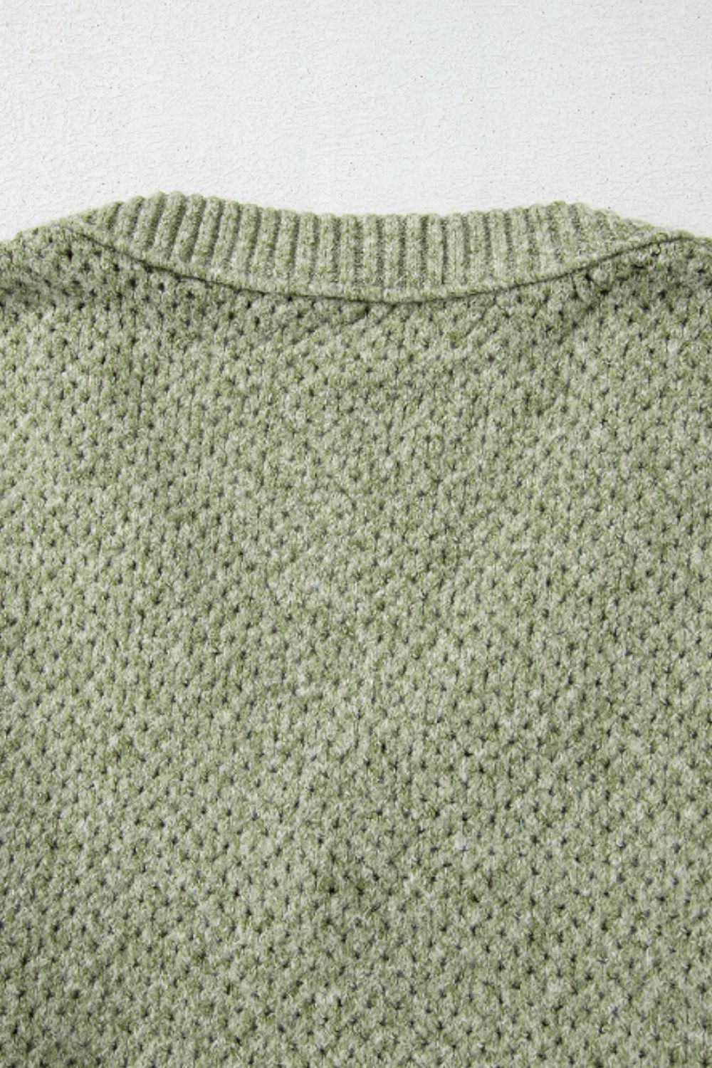 Matcha green open-knit slouchy V-neck sweater with ribbed neckline detail.