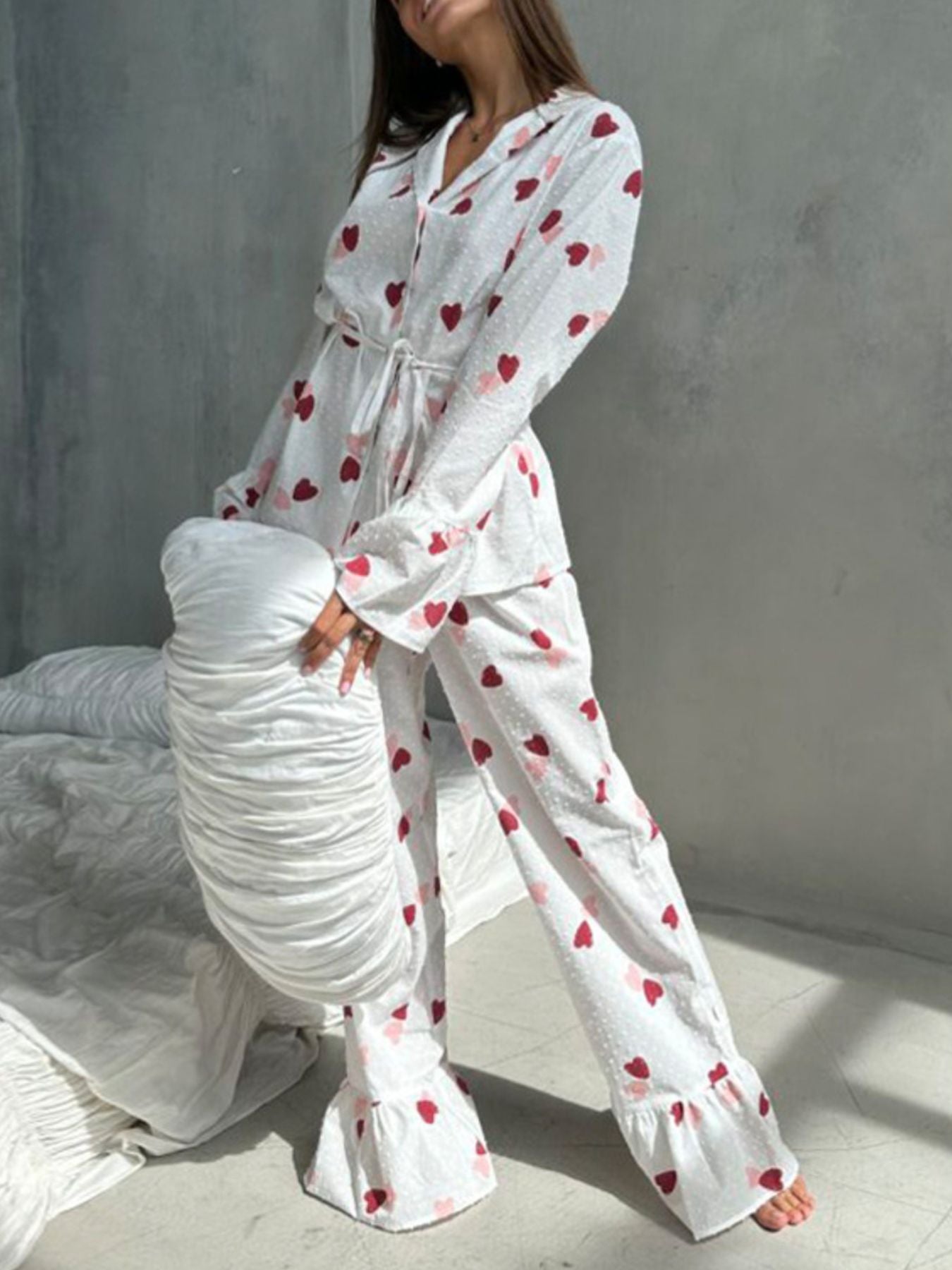 White cotton pajama set with red and pink heart print, button-down top, and ruffled pants.