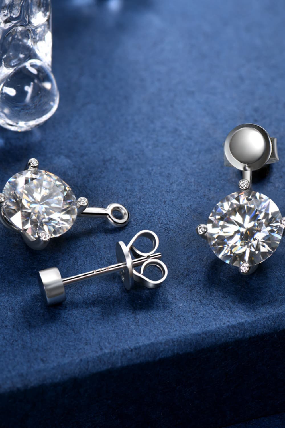 Silver moissanite stud and drop earrings with round cut center stones and small accent stones.