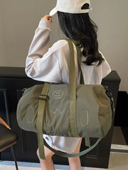 Green duffel bag with cheerful smiley face and abstract design, adjustable strap.