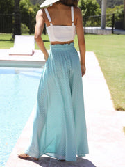 Turquoise palazzo trousers with a subtle geometric print and ruffled waist, styled with a white crop top.