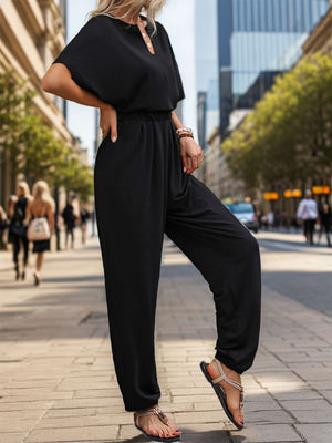 Black jumpsuit with short sleeves, keyhole neckline, and draped wide legs.